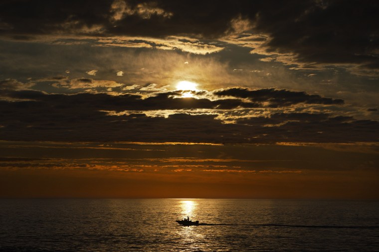 Image: An early-rising sport fisherman motors over calm seas on his way to striped bass fishing grounds off the coast of Kennebunkport, Maine, July 7, 2022.