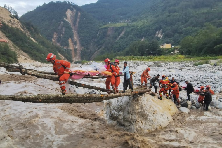 Rescuers workers carry survivors across a river after an earthquake in China's Sichuan Province on Monday. 