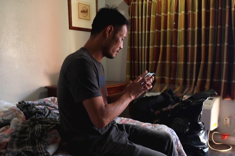 Jin uses a cellphone in his motel room.