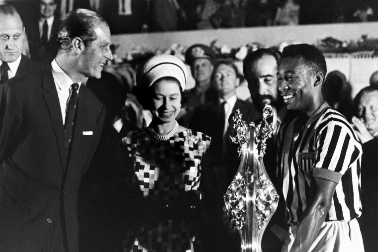 Queen Elizabeth II and her husband, Prince Philip, smile as they give a cup to Pele, right, at a soccer stadium in Rio de Janeiro, on Nov. 10, 1968.
