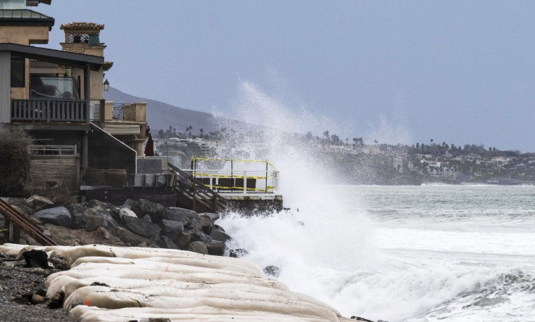 Waves crash into boulders in front of homes at Capistrano Beach