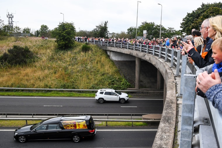 Members of the public stand on a bridge in Kinross, overlooking the M90 motorway, to pay their respects as they look at the hearse carrying the coffin of Queen Elizabeth II driving to Edinburgh to lie at rest on Sept. 11, 2022.