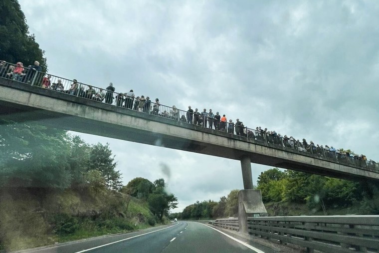 People line an overpass along the way to Edinburgh from Balmoral in Scotland on Sept. 11, 2022.