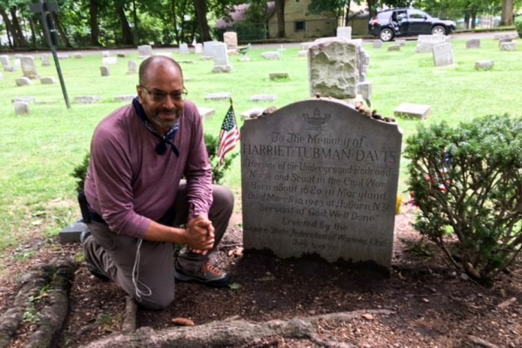 Ken Johnston kneels next to Harriet Tubman's tombstone in Auburn, N.Y.