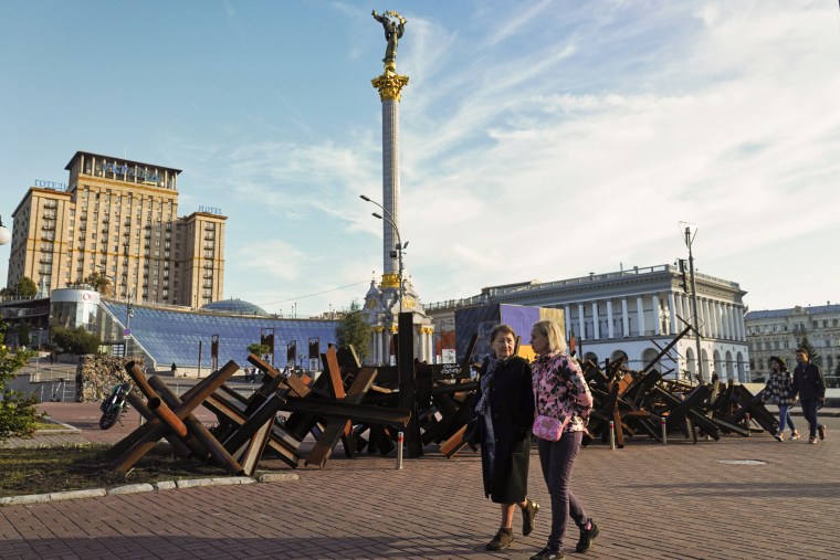 Image: Two women walk by rusted hedgehogs once put in the streets to block tanks and the Independence Monument in Kyiv, on  Sept. 11, 2022.