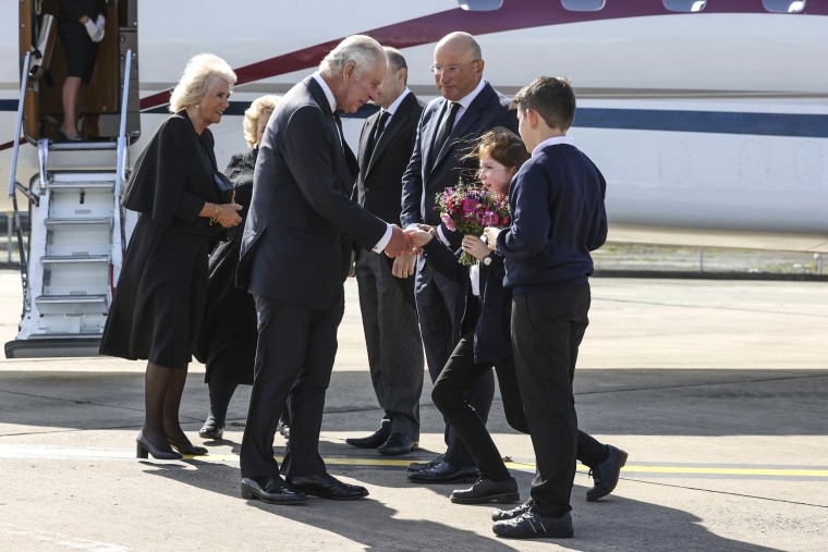 Image: The Queen Consort, left, is greeted by Lord Lieutenant of Belfast Fionnuala Jay-O'Boyle as King Chares III is greeted by, left to right, Secretary of State for Northern Ireland Chris Heaton-Harris, Chief Executive of Belfast City Airport Matthew Hall, Ella Smith aged 10, and Lucas Watt aged 10 as they arrive at Belfast City Airport, Northern Ireland, on Sept. 13, 2022.