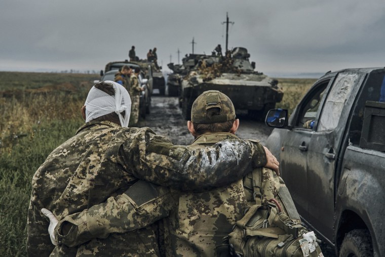 Image: A Ukrainian soldier helps a wounded fellow soldier on the road in the freed territory in the Kharkiv region, Ukraine, on Sept. 12, 2022.