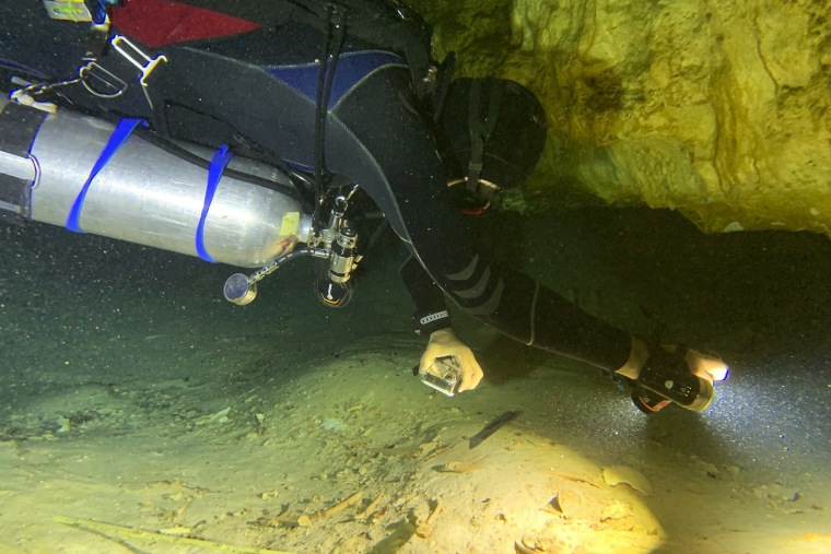 Aquatic archaeologist Octavio del Rio records a prehistoric human skeleton partly covered by sediment in an underwater cave in Tulum, Mexico, on Saturday.