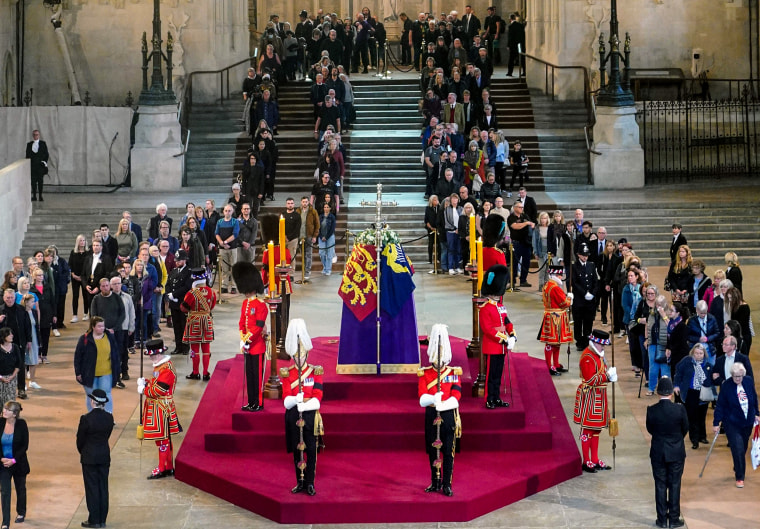 Mọi người ngồi trước quan tài của Nữ hoàng Elizabeth II, được phủ theo tiêu chuẩn hoàng gia với Vương miện, Orb và Scepter của Nhà nước Hoàng gia, nằm trong trạng thái trên quan tài tại Westminster Hall vào ngày 15 tháng 9 năm 2022, ở London.