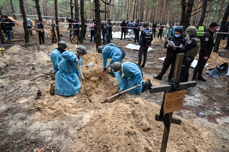 Image: Forensic technicians dig a grave in a forest on the outskirts of Izyum, eastern Ukraine on Sept. 16, 2022.