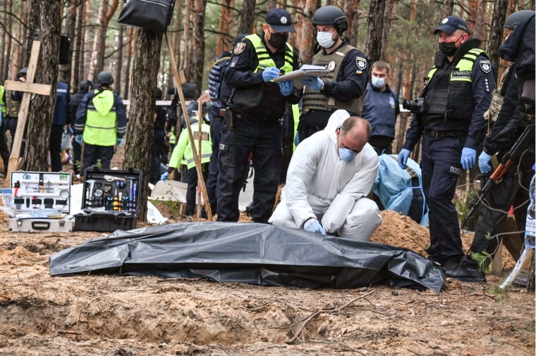 Image: A forensic technician closes a body bag in a forest on the outskirts of Izyum, eastern Ukraine on Sept. 16, 2022.
