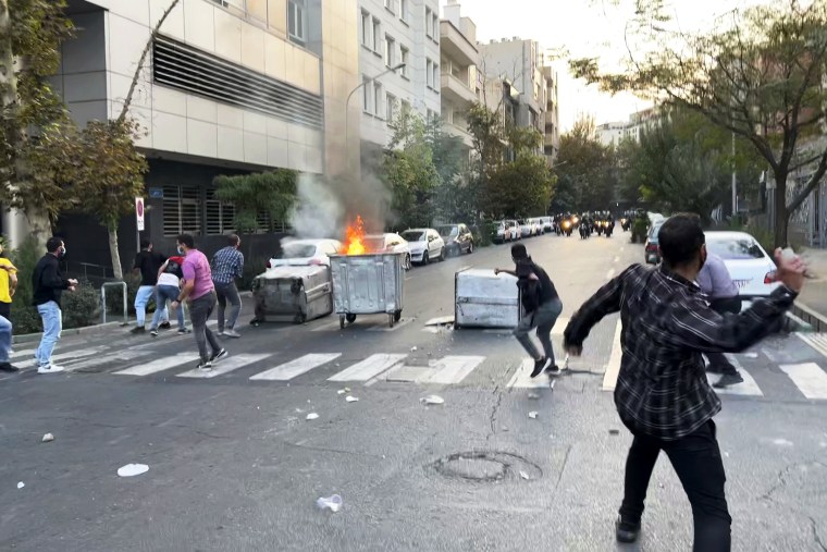 Protesters throw stones at anti-riot police during a protest over the death of a young woman who had been detained for violating the country's conservative dress code, in downtown Tehran, Iran, on Sept. 20, 2022.