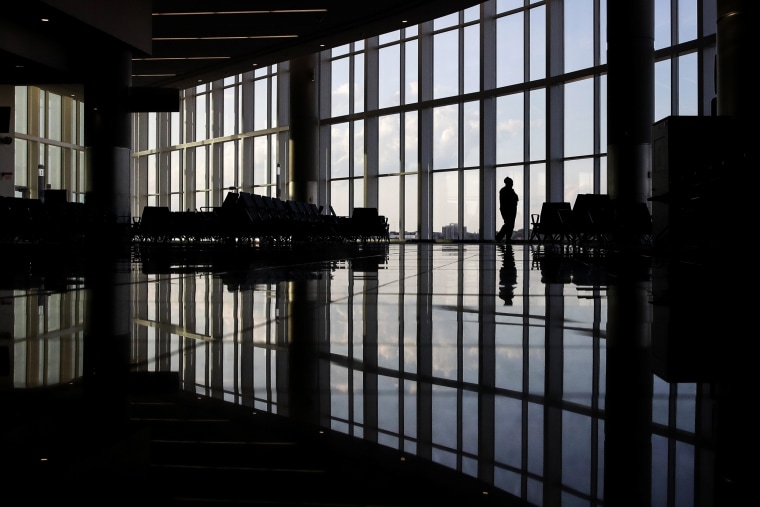 A woman looks through a window at a near-empty terminal at an airport in Atlanta on June 1, 2020.