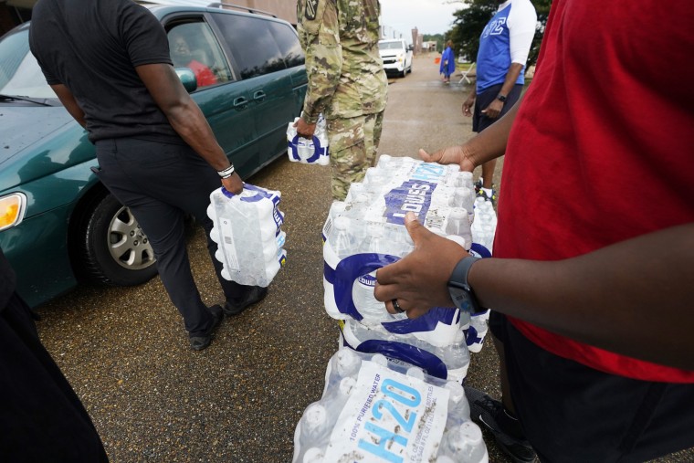 Volunteers distribute cases of water at a community drive-thru water distribution site