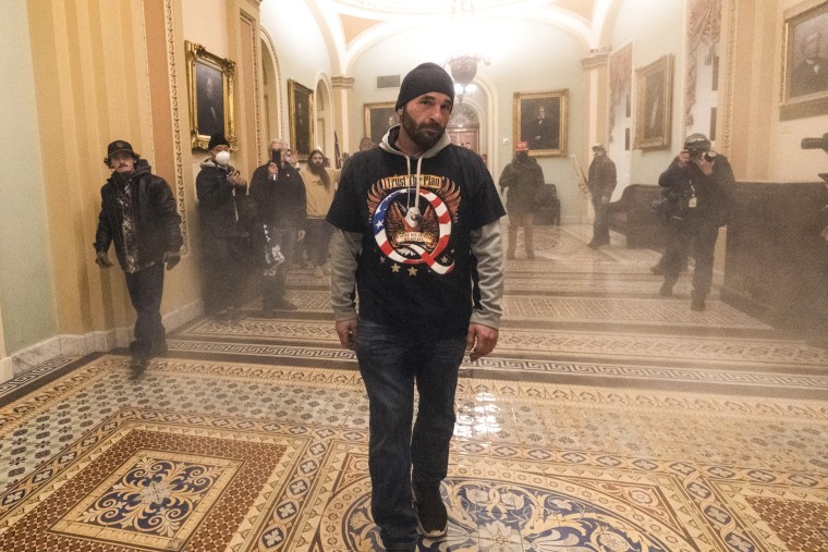 Smoke fills the walkway outside the Senate Chamber as supporters of President Donald Trump, including Doug Jensen, center, are confronted by Capitol Police officers on Jan. 6, 2021.