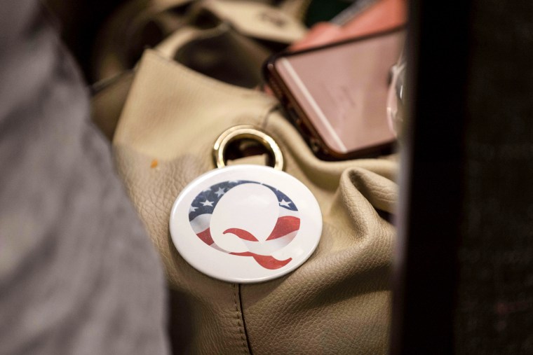 A QAnon conspiracy theory button sits affixed to the purse of an attendee of the Nebraska Election Integrity Forum on Aug. 27, 2022, in Omaha, Neb.