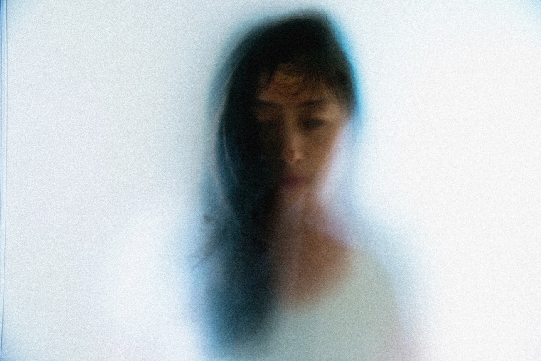Image: woman face peering through frosted glass
