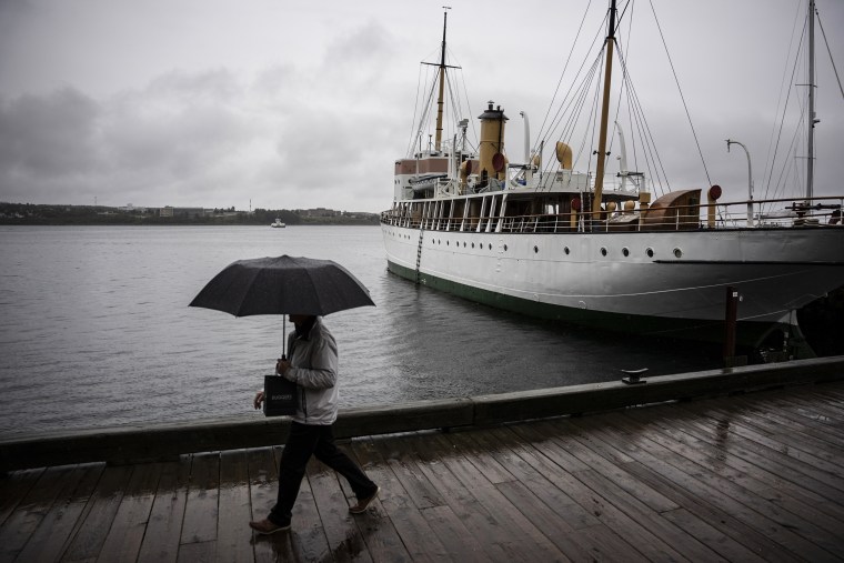 Image: A pedestrian shields themselves with an umbrella while walking along the Halifax waterfront as rain falls ahead of Hurricane Fiona making landfall in Halifax, on Sept. 23, 2022.