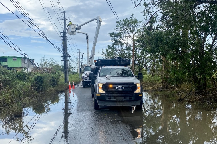 Workers with Luma Energy attempt to restore power on a flooded street in Cabo Rojo, Puerto Rico, on Sept. 24, 2022.