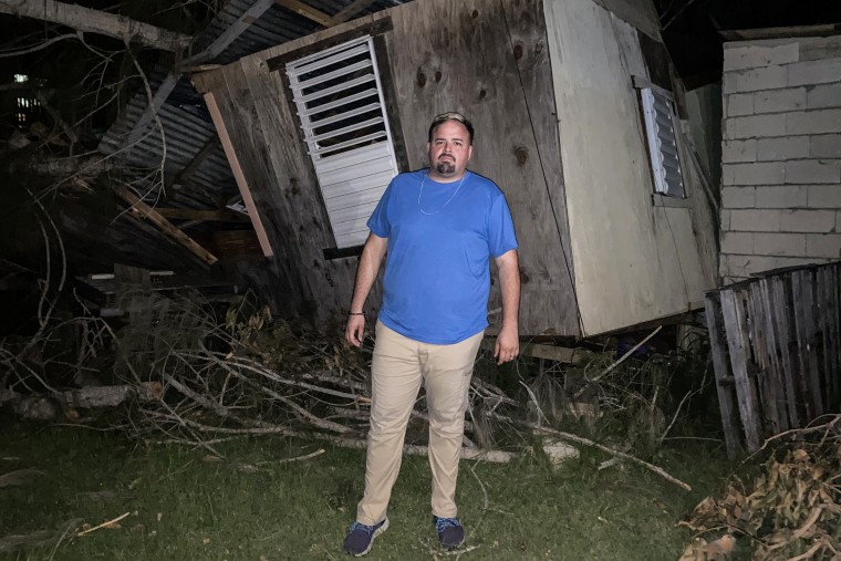 Hevel Velez Luciano, a community leader in Cabo Rojo, stands in front of a home destroyed by a downed tree in that region of Puerto Rico on Sept. 24, 2022.