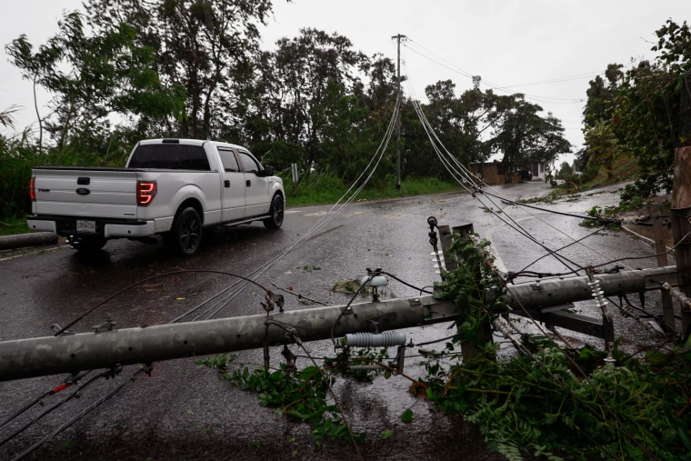 Hurricane Fiona hits Puerto Rico, knocking out power across the island. Downed power line stretching across a road, with a truck parked next to it.