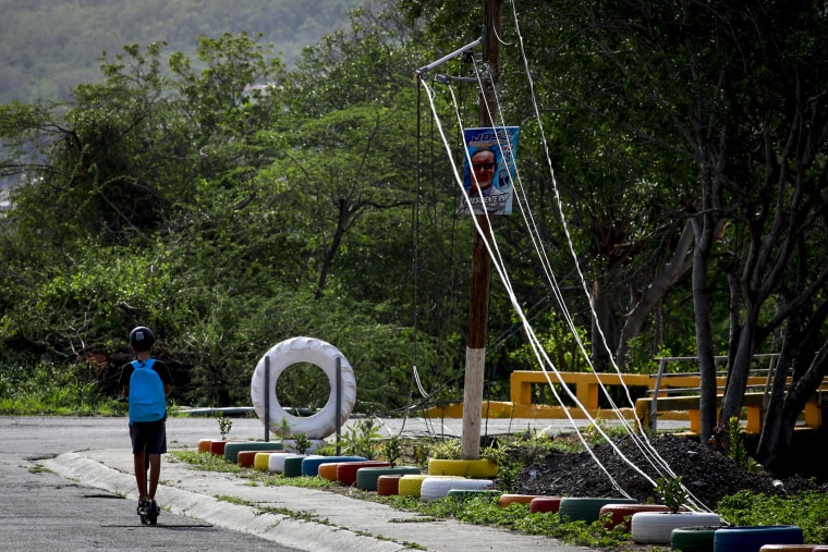 A kid rides a scooter past downed electricity lines on Sept. 20, 2022, in Salinas, Puerto Rico.