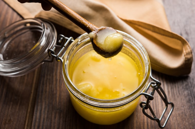 Desi Pure Ghee or clarified butter in glass or Copper container with spoon, selective focus