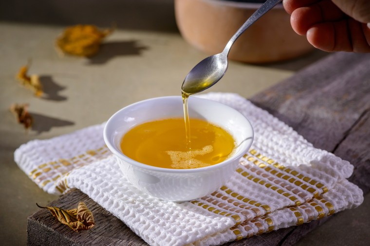 Ghee butter from India in white dinnerware container on wooden table.