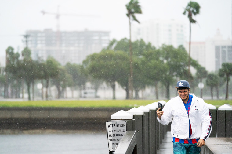 A man holds his phone on a dock in Sarasota, Fla.