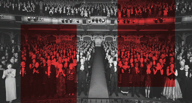 Theater audience standing in formal attire, applauding