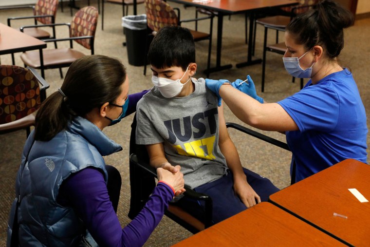 Image: Jamie Blank, left, holds her son, Ari, as he receives a Covid-19 vaccine from a healthcare worker in Bloomfield Hills, Mich., on May 13, 2021.