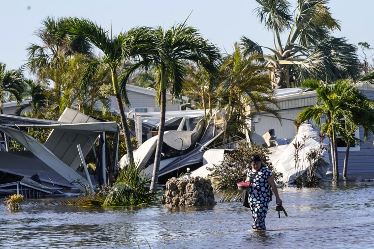 Image: Holly Nugyn walks out of her flooded neighborhood after Hurricane Ian passed by the area on Sept. 29, 2022, in Fort Myers, Fla.