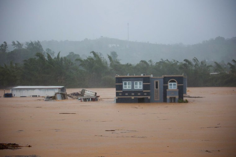 Tres personas dentro de una casa aguardan a ser rescatadas de las inundaciones provocadas por el huracán Fiona, el domingo 18 de septiembre de 2022, en Cayey, Puerto Rico.