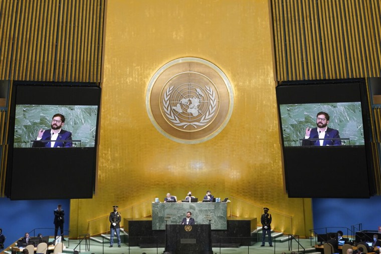 Gabriel Boric, el presidente chileno, habla desde el podio de la Asamblea General de la ONU al centro. Detrás suyo hay dos pantallas mostrando el discurso y un muro con detalles dorados y el símbolo de las Naciones Unidas