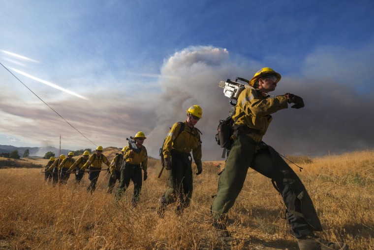 Bomberos caminan en fila durante un incendio forestal en Castaic, California, el miércoles 31 de agosto de 2022.