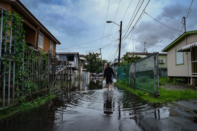 Un hombre camina por una calle inundada en el barrio Juana Matos de Catano, Puerto Rico, el 19 de septiembre de 2022, tras el paso del huracán Fiona.