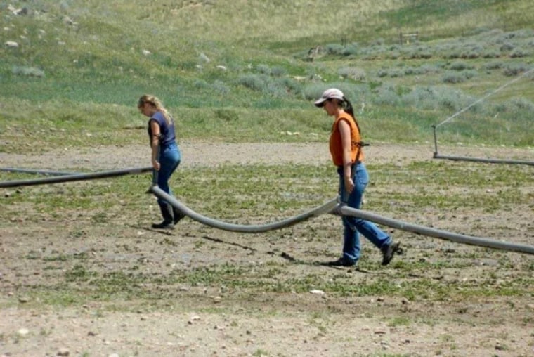 Clarice Steg (izq.) y Maggie Higgins cargan tuberías de irrigación en el rancho Trinity.
