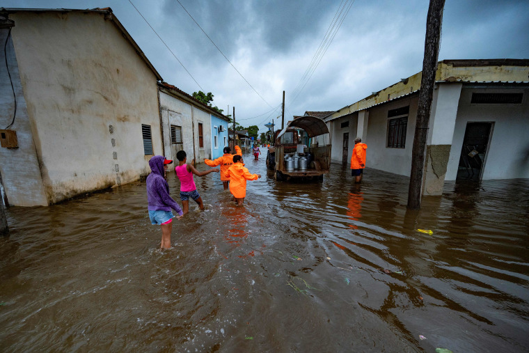 La gente camina por una calle inundada en Batabano, Cuba, el 27 de septiembre de 2022, durante el paso del huracán Ian.