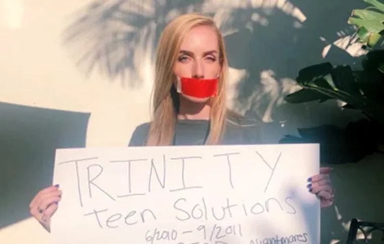 Kelsie VanMeveren sostiene una pancarta de protesta contra el rancho Trinity.