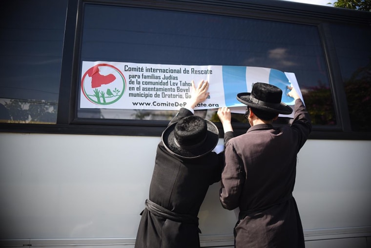 Miembros de una comunidad judía ortodoxa colocan una etiqueta del Comité Internacional de Rescate para Familias Judías del Asentamiento Lev Tahor en la ventana de un autobús en la ciudad de Guatemala, el 25 de septiembre de 2016. 