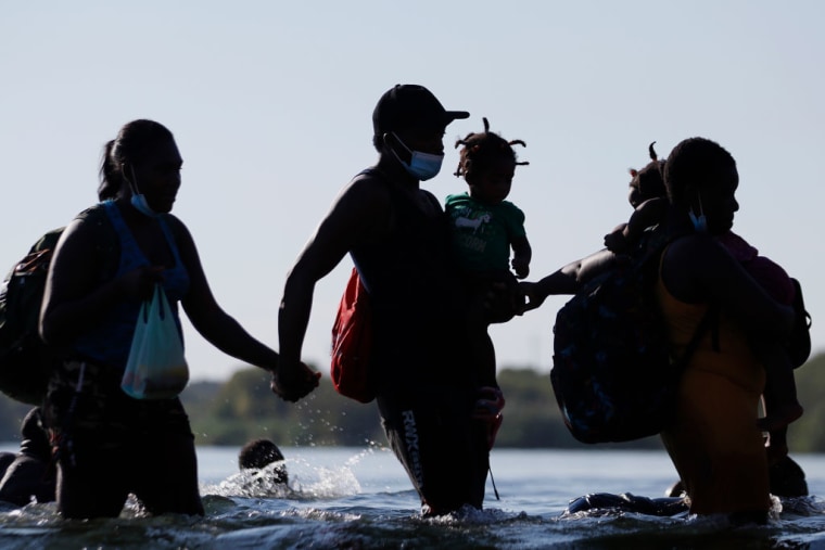 Migrantes tomados de la mano cruzan el Río Grande en Ciudad Acuña en su camino hacia el lado estadounidense el 17 de septiembre de 2021 en Ciudad Acuña, México.