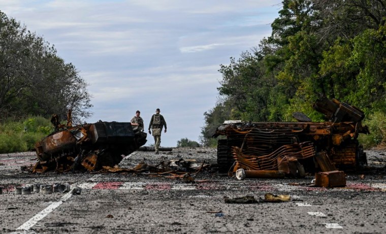 Soldados ucranianos en una carretera de Kharkiv entre restos de vehículos destruidos, el 10 de septiembre de 2022.