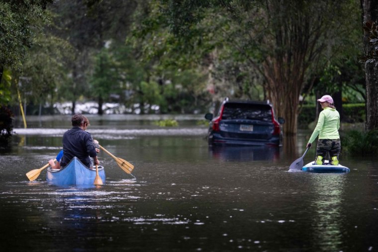Unos residentes se desplazan en canoa y paddle board en una calle totalmente inundada en Orlando, Florida, el 28 de septiembre de 2022.