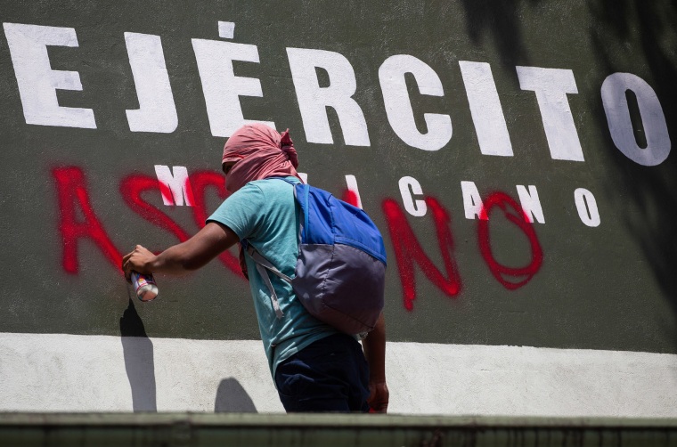 Un estudiante de Ayotzinapa pinta la entrada de la Base Militar 1 durante una protesta exigiendo justicia antes del 8º aniversario de la desaparición de los estudiantes en Iguala, en la Ciudad de México, México el 23 de septiembre de 2022.