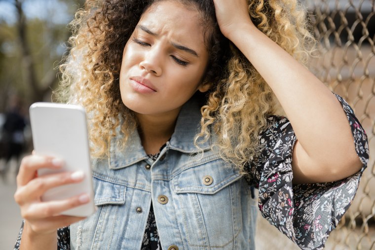 Unhappy Mixed Race woman texting on cell phone