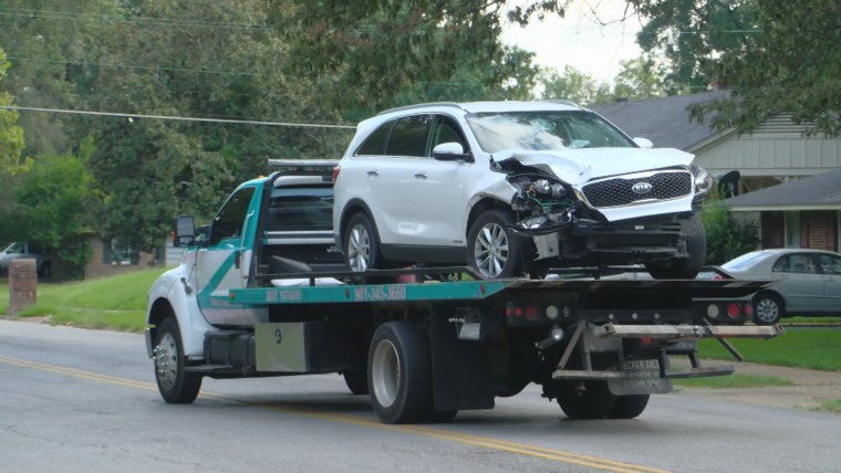 The smashed white Kia is towed from the scene.