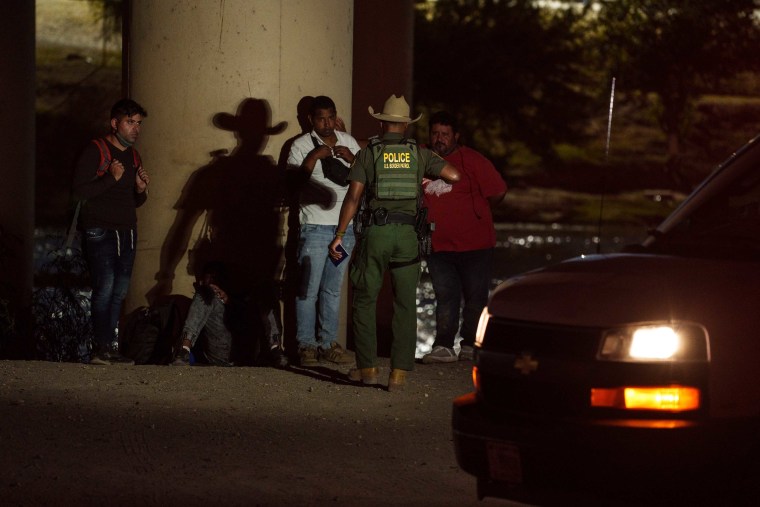 Un agente de la Patrulla Fronteriza de EE.UU. habla con migrantes bajo el puente internacional Camino Real en Eagle Pass, Texas, EE.UU.