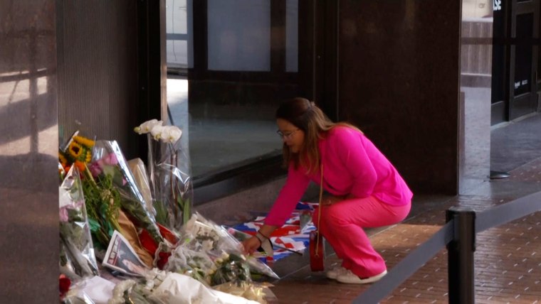 A woman places flowers at the foot of a memorial made for Queen Elizabeth II located in New York City.