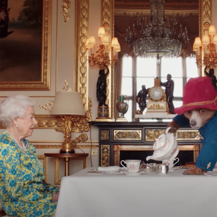 Paddington Bear, right, pours tea for Queen Elizabeth II in a video commemorating her Platinum Jubilee. 
