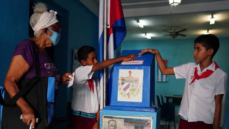 Niños ayudan a una votante a emitir su boleta en un colegio electoral durante el referéndum del nuevo Código de las Familias en La Habana, Cuba, el 25 de septiembre de 2022.